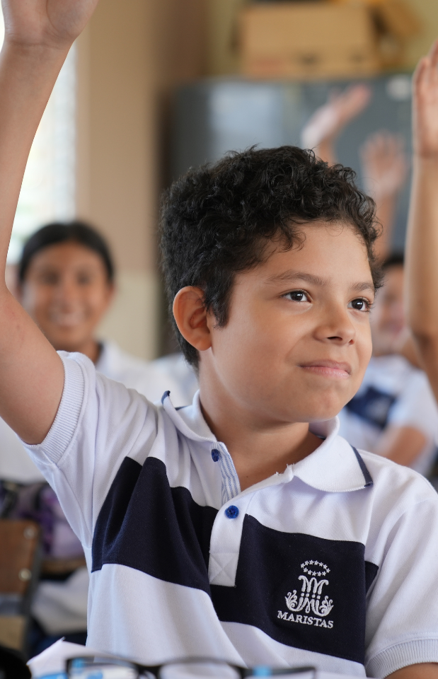 Niño participando en clase, levantando la mano con entusiasmo durante una actividad educativa. Representa la diversidad de estilos de aprendizaje en el aula.